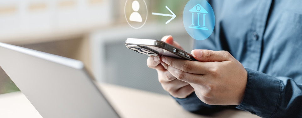 Online Banking. Mann überweist mit Handy und Laptop Geld.