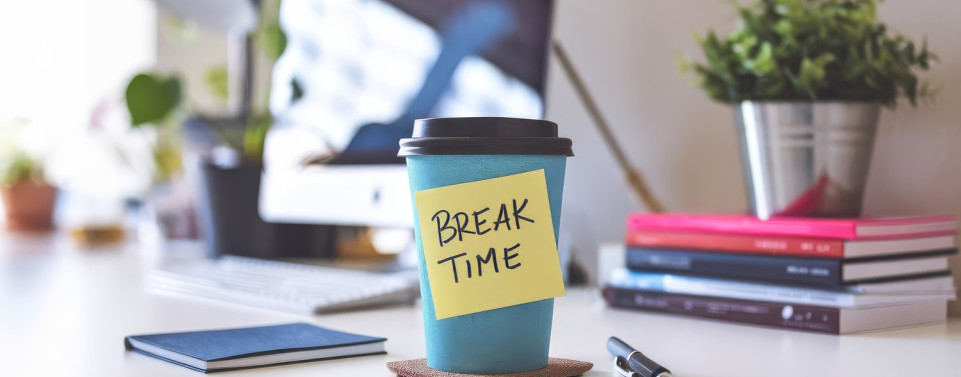 Ein Kaffeebecher mit der Aufschrift "Break Time" auf einem Schreibtisch. Pause während der Arbeitszeit