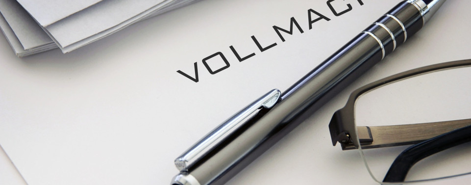 Dokument mit dem Titel "Vollmacht" darunter liegt ein Stift und eine Brille 