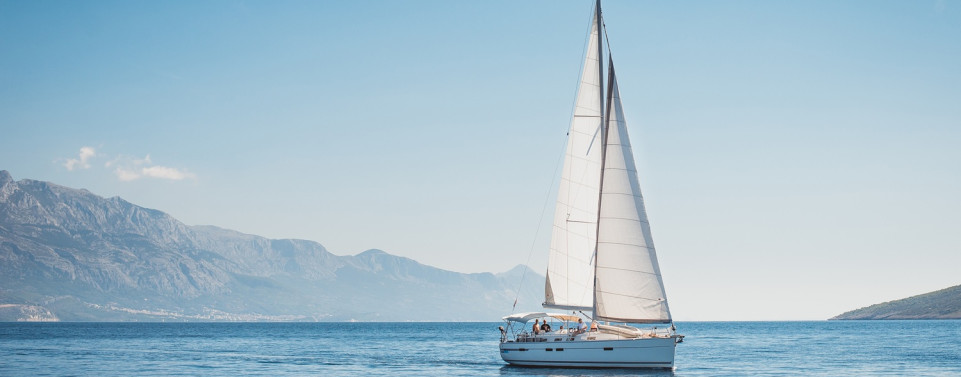 Ein Segelboot auf dem Wasser, im Hintergrund die Küste.