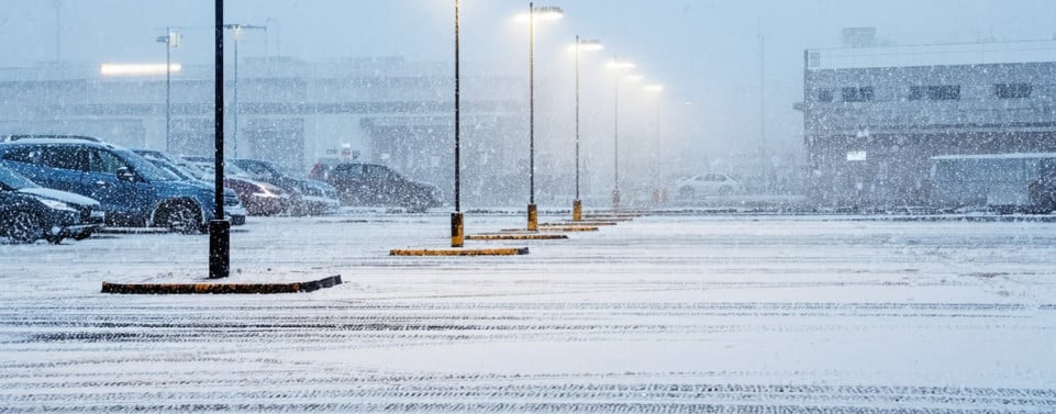 Parkplatz mit leuchtenden Laternen im Winter mit Schnee.
