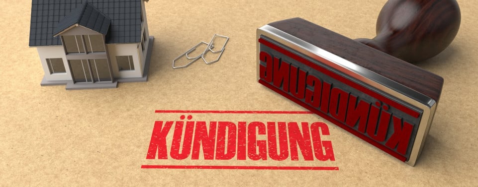 Stempel mit dem Wort "Kündigung. Ein kleines Modellhaus neben dem Stempel.