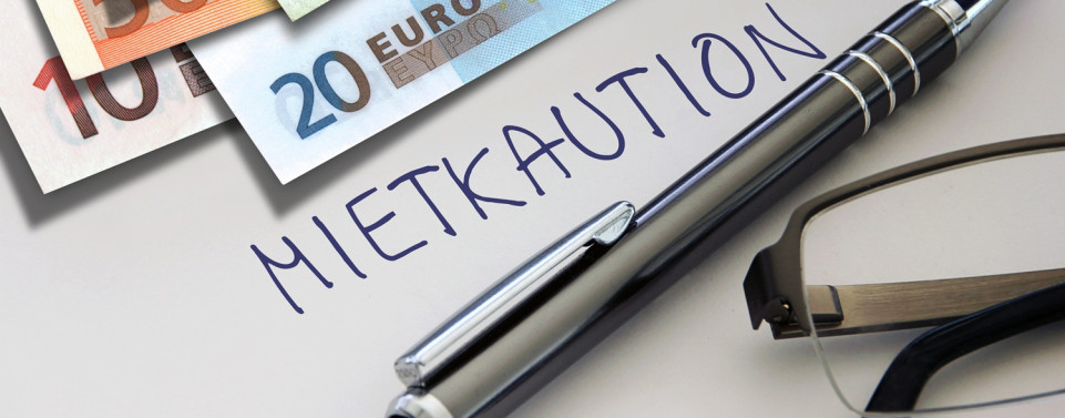 Geldscheine, ein Stift und eine Brille liegen auf einem Blatt mit der Aufschrift "Mietkaution"