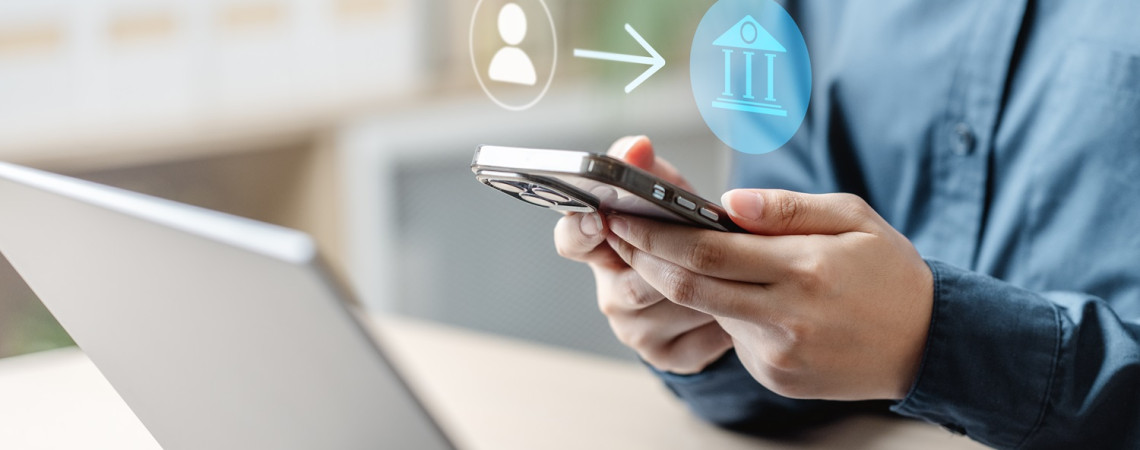 Online Banking. Mann überweist mit Handy und Laptop Geld.