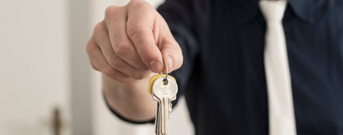 Gebrauchsüberlassung: Mann hält Wohnungsschlüssel hin.