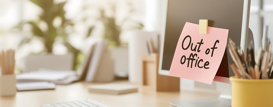Symbolbild für Mindesturlaub. Ein Schreibtisch mit einem Bildschirm an dem ein Zettel mit "Out of office" hängt.