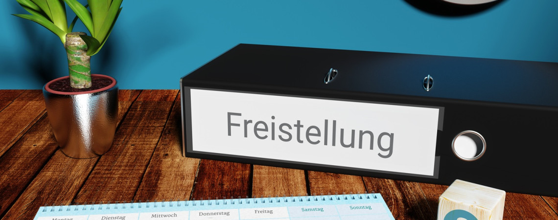 Ordner mit Aufschrift "Freistellung" liegt auf einem Tisch. Ein Kalender mit und ein Würfel mit deinem Paragrafen-Zeichen liegen auf dem Tisch. 