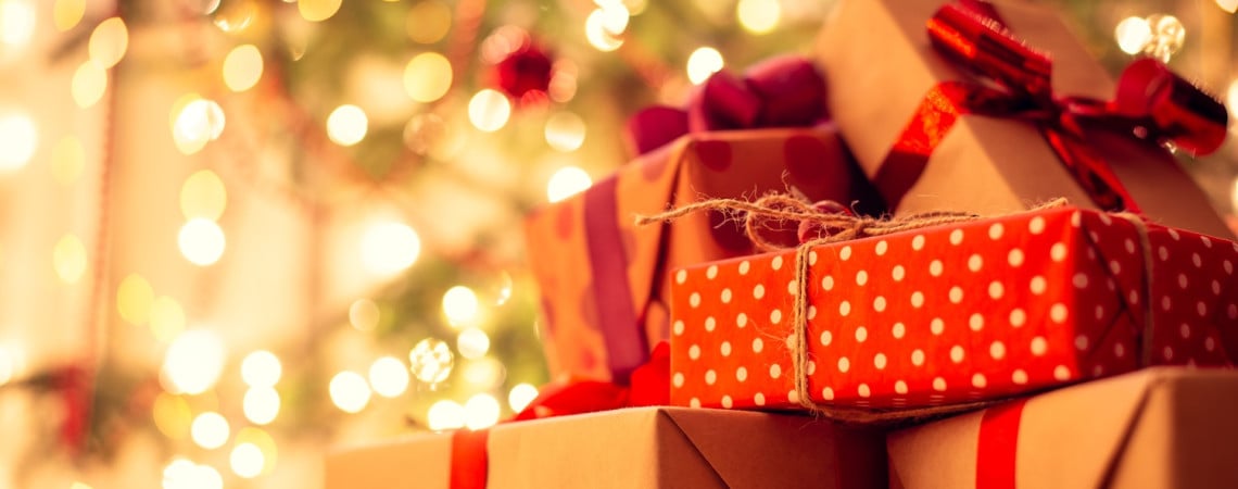 Geschenke und im Hintergrund ein geschmückter Weihnachtsbaum.