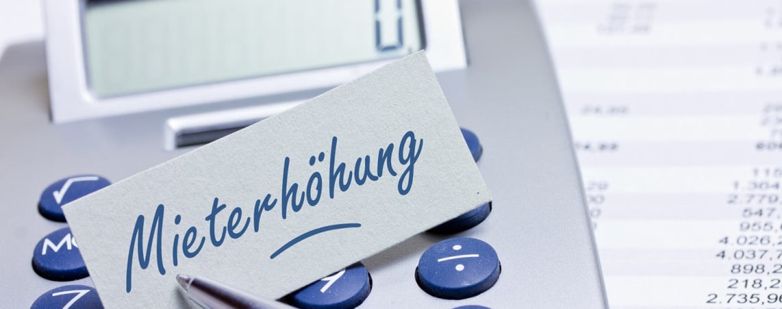 Taschenrechner auf dem ein Papier mit der Aufschrift "Mieterhöhung" liegt. 