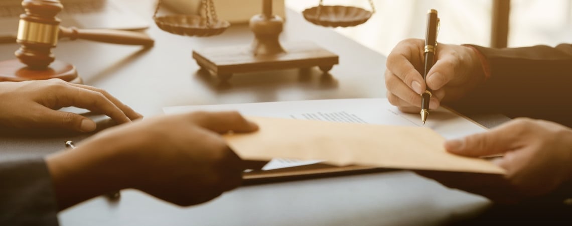 Hand übergibt einem anderen einen Umschlag. Andere Person unterschreibt ein Dokument.