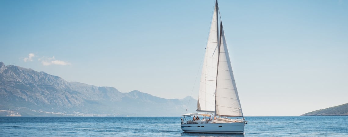 Ein Segelboot auf dem Wasser, im Hintergrund die Küste.