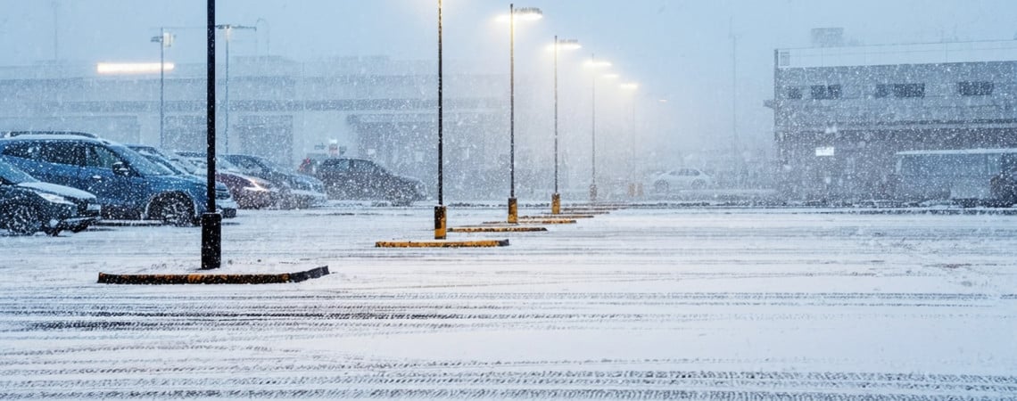 Parkplatz mit leuchtenden Laternen im Winter mit Schnee.