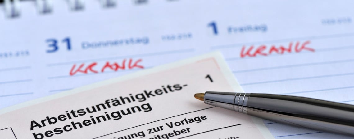 Arbeitsunfähigkeitsbescheinigung mit Stift liegen auf einem Kalender.