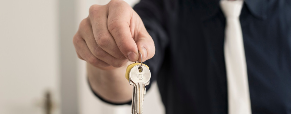 Gebrauchsüberlassung: Mann hält Wohnungsschlüssel hin.