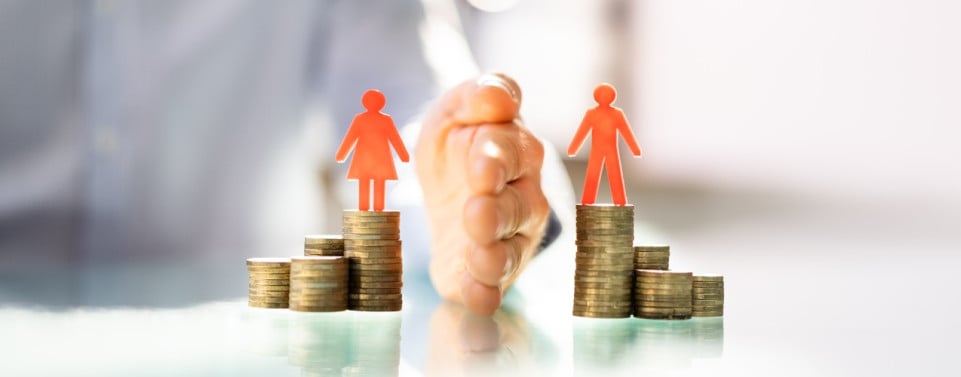 Zwei Stapel mit Münzen werden durch eine Hand getrennt. Auf dem einen steht eine Figur als Frau und auf dem anderen ein Mann.