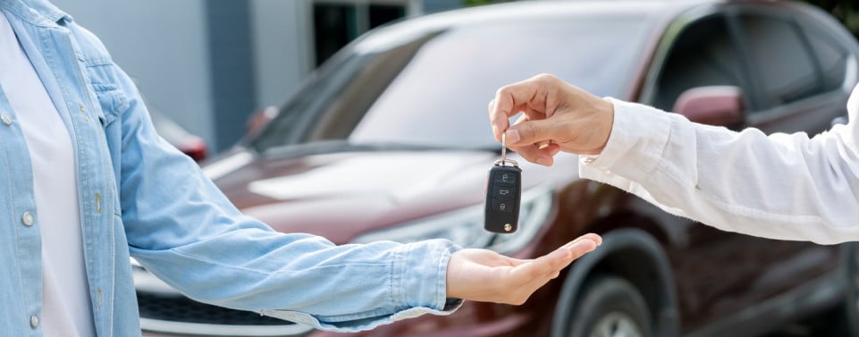 Mann kauf Gebrauchtwagen. Ein Man übergibt Autoschlüssel an den anderen.