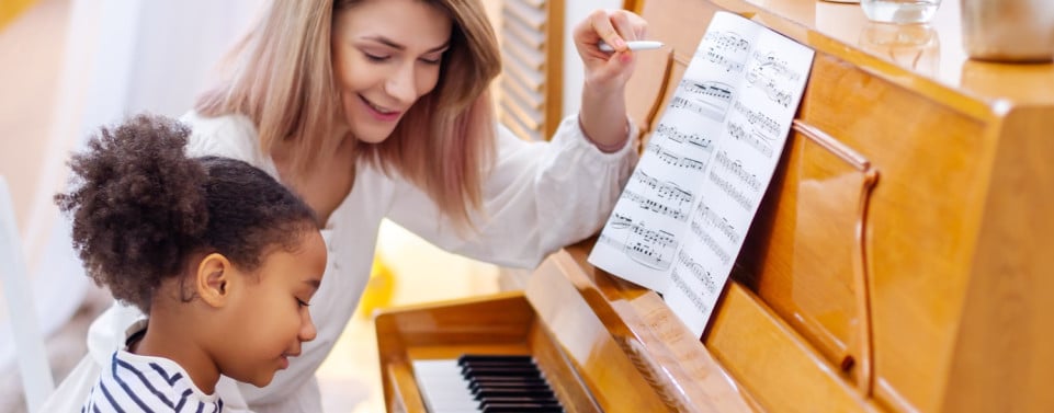 Musikschullehrerin mit Kind am Klavier.