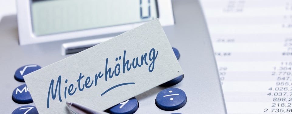 Taschenrechner auf dem ein Papier mit der Aufschrift "Mieterhöhung" liegt. 