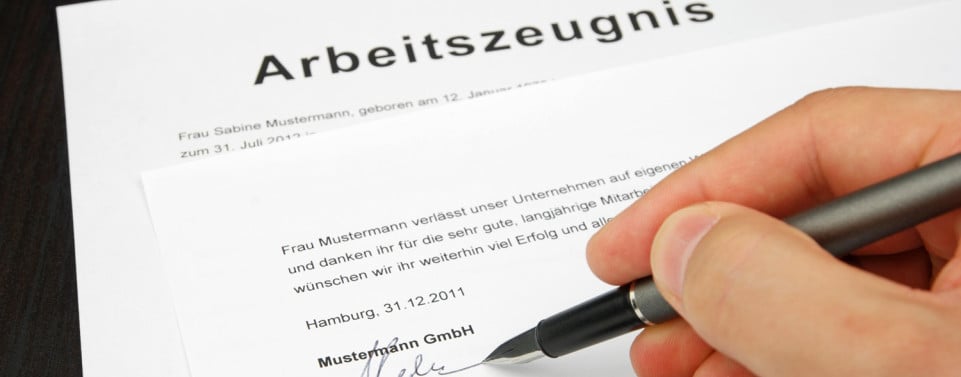 Arbeitszeugnis und Hand, die es unterschreibt.