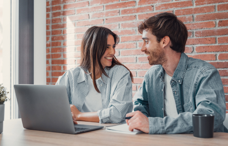 Junges Paar schaut sich an und arbeitet an Laptop